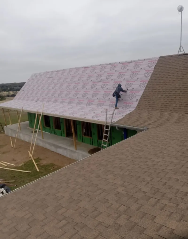 Worker preparing underlayment for a metal roof installation in El Mirage